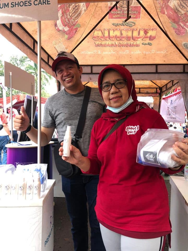 Dua pelanggan tersenyum dan mengacungkan jempol sambil memegang produk RAR Shoescare