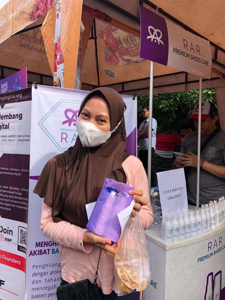 Pelanggan memegang tas produk RAR Shoescare di booth event
